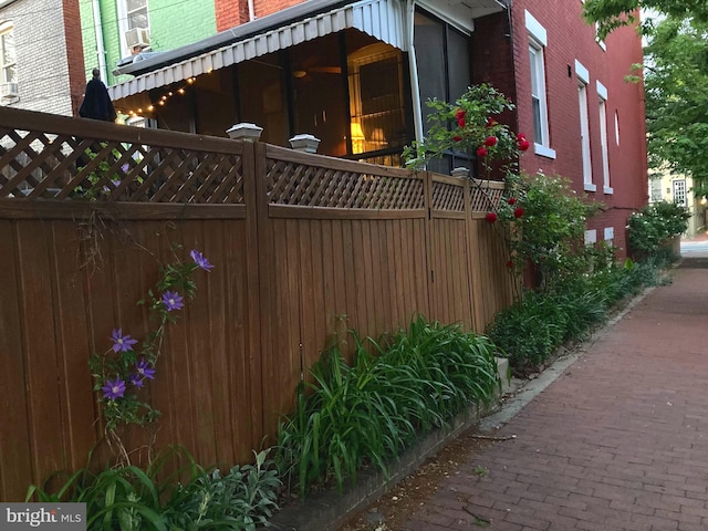 view of side of home with brick siding, fence, and cooling unit