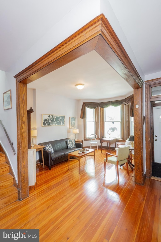 living room featuring light wood-style floors, baseboards, and stairs