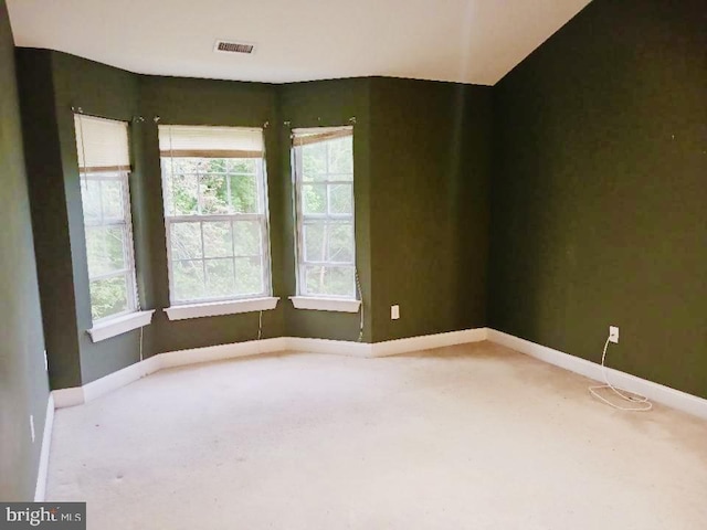 empty room with light carpet, baseboards, and healthy amount of natural light