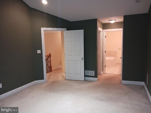 unfurnished bedroom featuring carpet flooring, baseboards, and ensuite bath