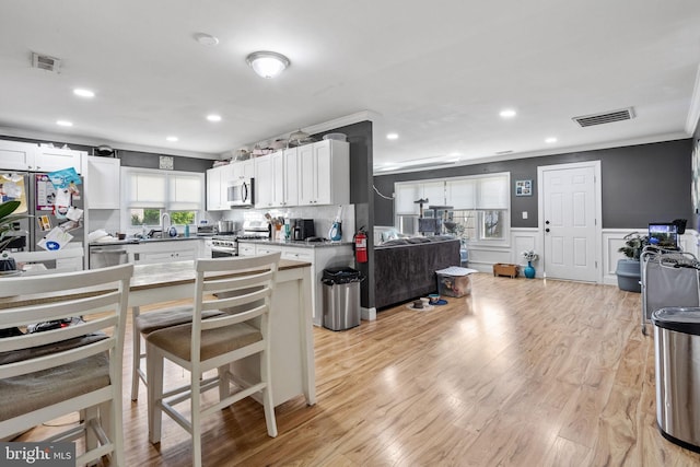 12 Bloomfield Ln, Willingboro, NJ 08046 - kitchen with crown molding, appliances with stainless steel finishes, white cabinetry, open floor plan, and a wainscoted wall
