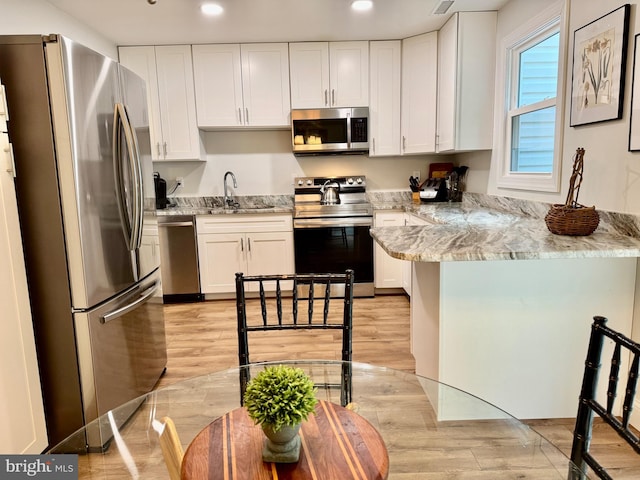 1410 Foxwood Ct, Annapolis, MD 21409 - kitchen with stainless steel appliances, a peninsula, white cabinetry, a sink, and light wood finished floors