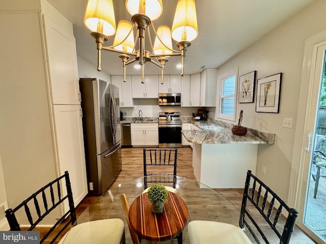 1410 Foxwood Ct, Annapolis, MD 21409 - kitchen featuring stainless steel appliances, white cabinets, a chandelier, a sink, and a peninsula