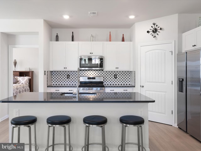 832 Red Maple Rd, Smyrna, DE 19977 - kitchen featuring stainless steel appliances, dark countertops, light wood-style floors, tasteful backsplash, and recessed lighting