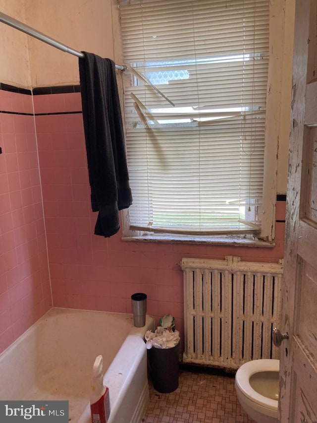 full bath with radiator, a bath, and toilet