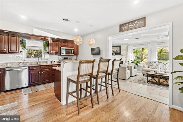 kitchen featuring appliances with stainless steel finishes, light wood-type flooring, a kitchen breakfast bar, plenty of natural light, and recessed lighting