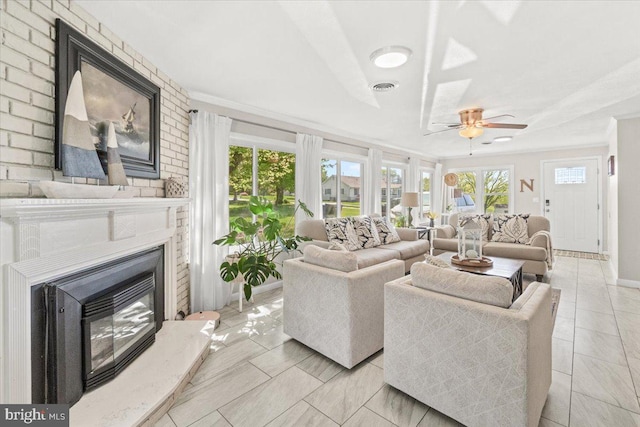 living area featuring a brick fireplace, ceiling fan, ornamental molding, and baseboards