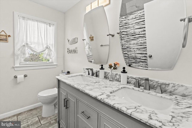 full bath with toilet, baseboards, double vanity, and a shower with curtain
