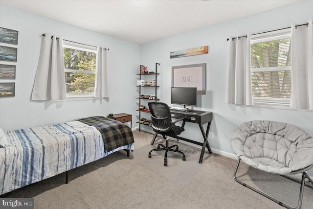 carpeted bedroom with multiple windows, an office area, and baseboards