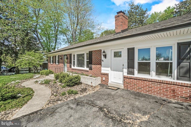 view of front of home featuring brick siding and a chimney