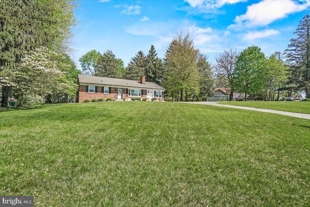 single story home with a front yard, a chimney, and brick siding