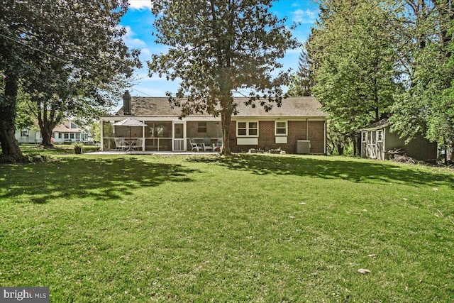 rear view of house featuring a sunroom and a lawn
