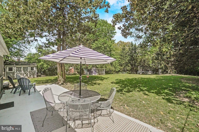 view of patio with a shed, outdoor dining space, a trampoline, and an outbuilding