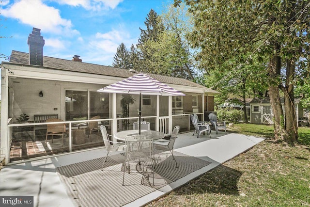 view of patio / terrace featuring a storage unit, an outbuilding, and outdoor dining area