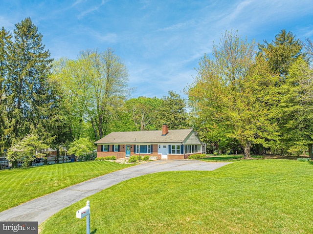 view of front of property with a front yard, a chimney, and driveway