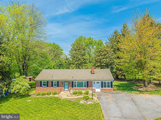view of front of home with brick siding, a chimney, and a front yard