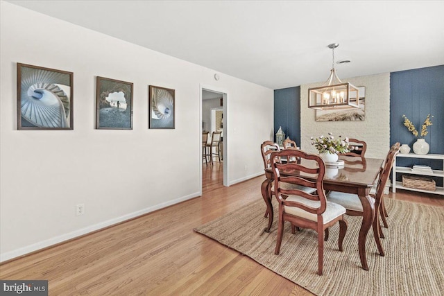 dining room featuring a chandelier, wood finished floors, and baseboards