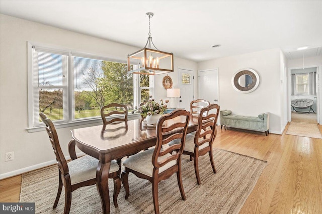 dining space with baseboards, a chandelier, light wood-style floors, and attic access