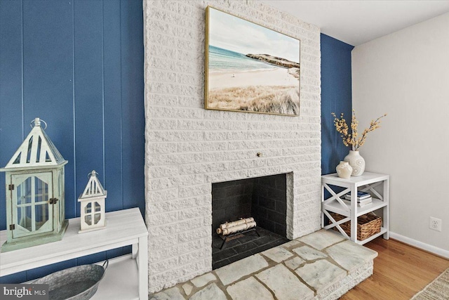detailed view of wood finished floors, baseboards, and a fireplace