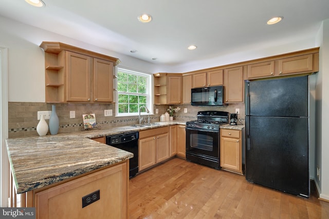 5513 Notched Beak Ct, Waldorf, MD 20601 - kitchen with open shelves, black appliances, light wood finished floors, light stone counters, and a peninsula