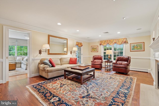 living room with healthy amount of natural light, a baseboard radiator, crown molding, wood finished floors, and recessed lighting