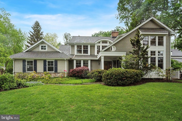 shingle-style home with a chimney and a front yard