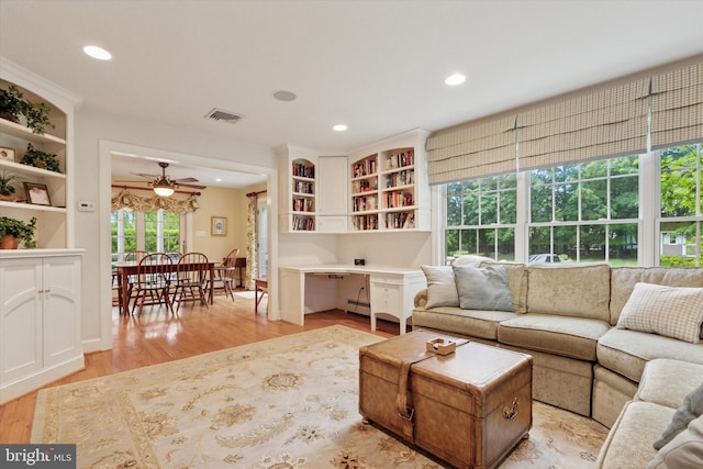living area with light wood-style flooring, recessed lighting, ceiling fan, a baseboard heating unit, and built in desk