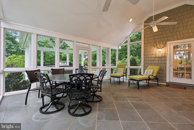 sunroom with ceiling fan, high vaulted ceiling, outdoor dining area, and tile patterned flooring