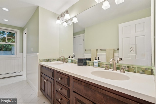 full bathroom featuring a skylight, wainscoting, a baseboard radiator, double vanity, and tile patterned floors