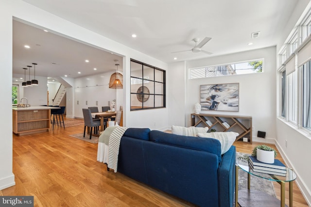 living area featuring stairs, light wood-style floors, a ceiling fan, recessed lighting, and baseboards