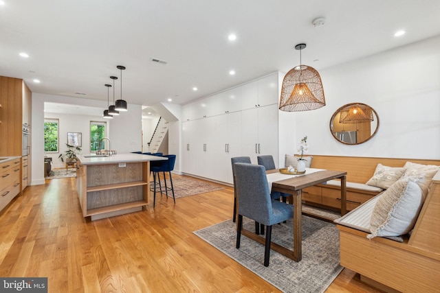 dining space featuring stairs, light wood finished floors, and recessed lighting