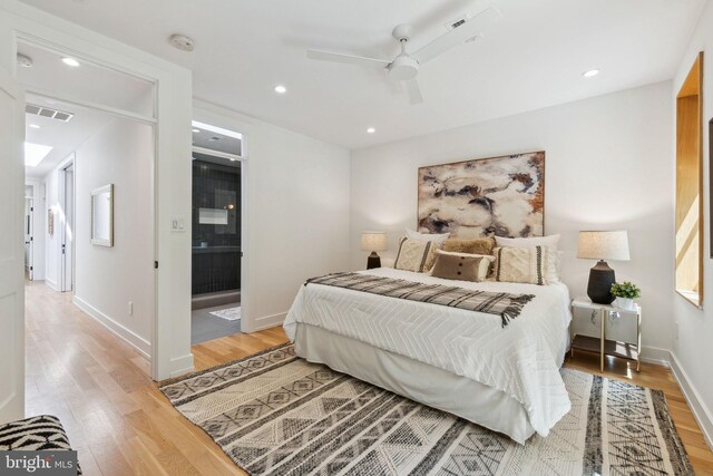 bedroom featuring light wood finished floors, recessed lighting, baseboards, ceiling fan, and ensuite bathroom