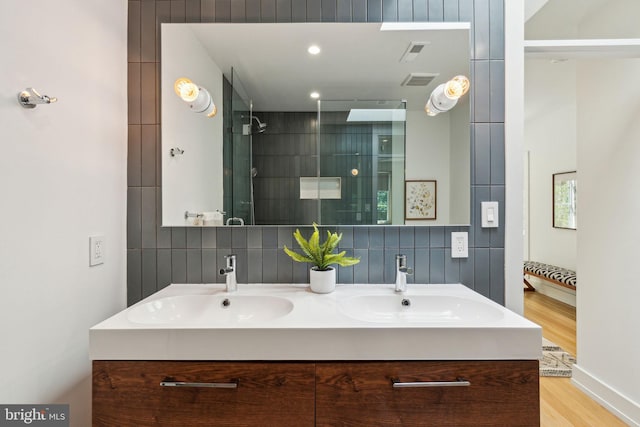 full bath with wood finished floors, tiled shower, backsplash, and double vanity