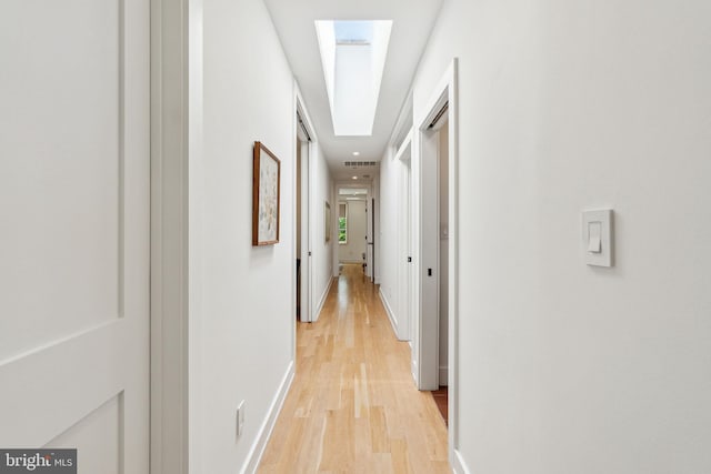 hall with light wood-style flooring and baseboards