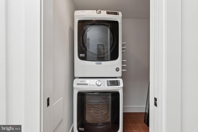laundry area with stacked washer and clothes dryer, tile patterned flooring, and baseboards