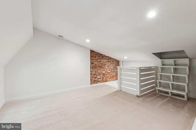 unfurnished living room with vaulted ceiling, carpet flooring, recessed lighting, brick wall, and baseboards