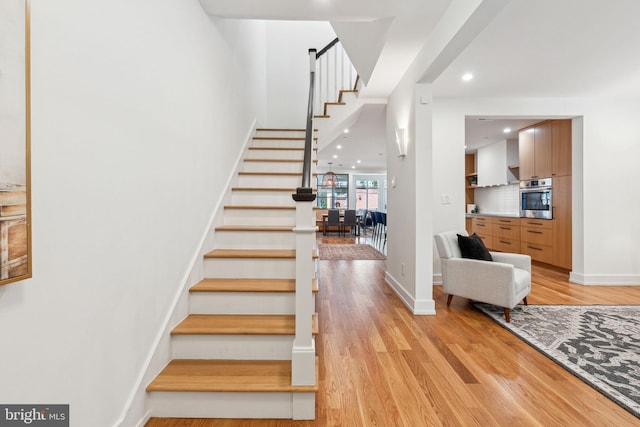 staircase featuring wood finished floors, recessed lighting, and baseboards