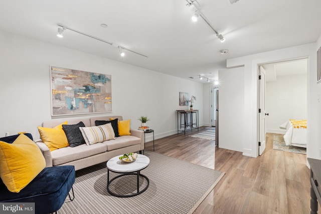 living room with rail lighting, light wood-style flooring, and baseboards