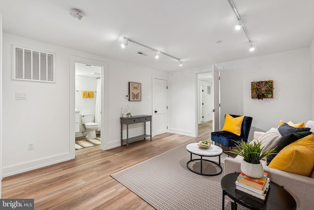 living area with track lighting, light wood-type flooring, and baseboards