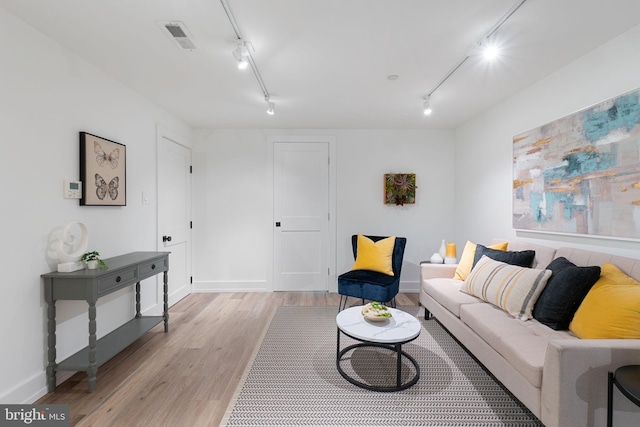 living room with rail lighting, light wood-style floors, and baseboards