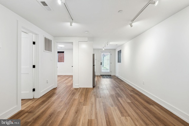 spare room with rail lighting, wood finished floors, and baseboards