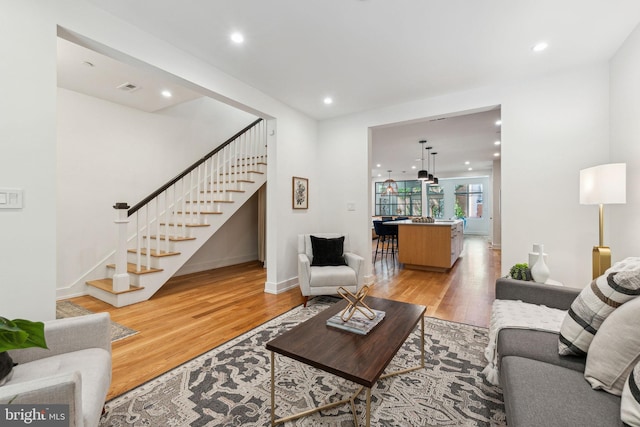 living area with stairway, light wood-style flooring, recessed lighting, and baseboards