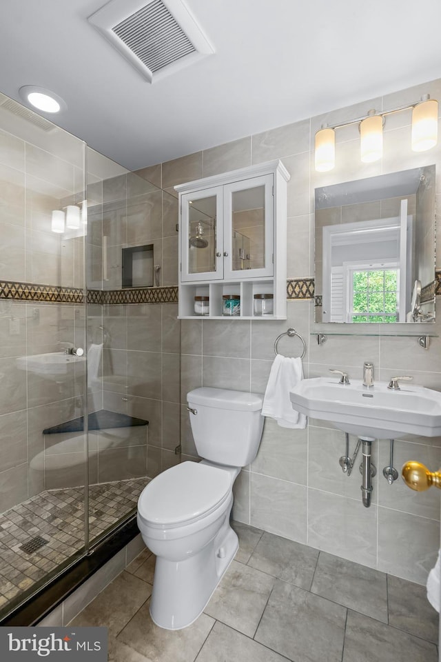 7029 Leewood Forest Dr, Springfield, VA 22151 - bathroom featuring toilet, a stall shower, tile patterned floors, tile walls, and a sink