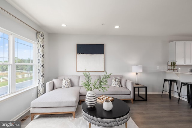 living room featuring dark wood-type flooring, baseboards, and recessed lighting