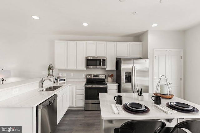kitchen with stainless steel appliances, a sink, recessed lighting, white cabinets, and dark wood-style floors
