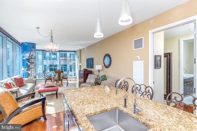 1414 S Penn Sq Unit 18H, Philadelphia, PA 19102 - kitchen featuring a sink, wood finished floors, open floor plan, light stone counters, and hanging light fixtures
