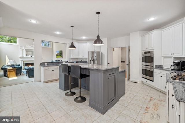 18309 Eldorado Way, Leesburg, VA 20176 - kitchen featuring stainless steel appliances, white cabinetry, a kitchen breakfast bar, light stone countertops, and recessed lighting