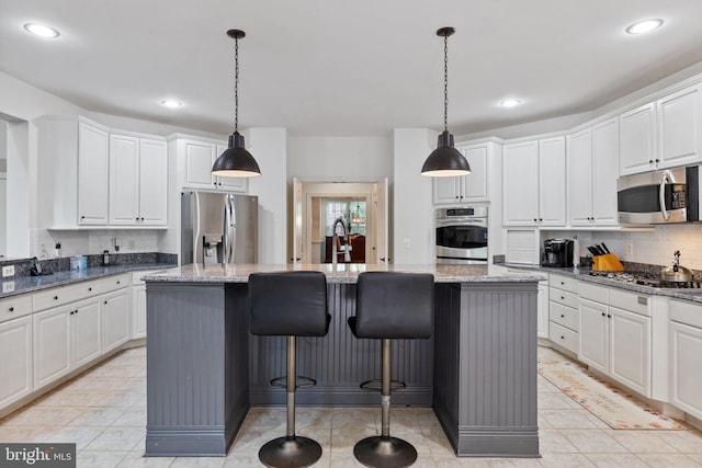 18309 Eldorado Way, Leesburg, VA 20176 - kitchen featuring appliances with stainless steel finishes, white cabinets, decorative backsplash, a kitchen island, and recessed lighting
