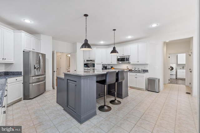 18309 Eldorado Way, Leesburg, VA 20176 - kitchen featuring appliances with stainless steel finishes, washer / clothes dryer, white cabinets, a center island with sink, and recessed lighting