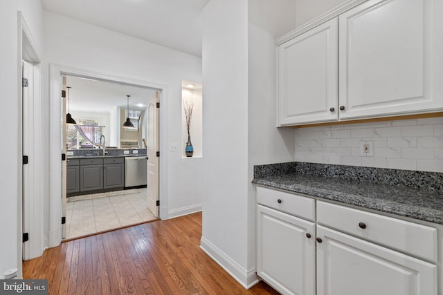 18309 Eldorado Way, Leesburg, VA 20176 - kitchen with stainless steel dishwasher, light wood-type flooring, backsplash, white cabinetry, and baseboards